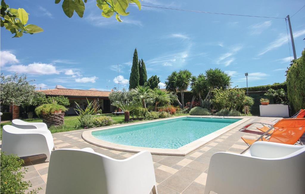 een zwembad in een tuin met witte stoelen bij Vento Di Mare in Porto Palo