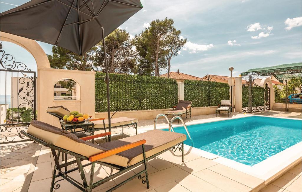 - une piscine avec une table et un parasol dans l'établissement Cozy Home In Makarska With Jacuzzi, à Makarska