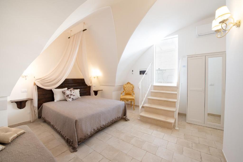 a white bedroom with a bed and a staircase at Il Vecchio Frantoio in Pezze di Greco