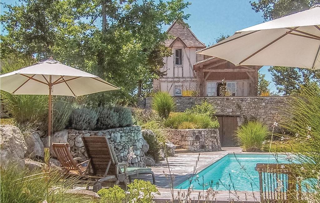 a pool with chairs and umbrellas and a house at Amazing Home In Beauville With 6 Bedrooms, Wifi And Outdoor Swimming Pool in Beauville