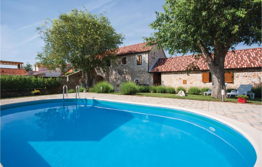 a large blue swimming pool in front of a house at Amazing Home In Lozovac With Kitchen in Lozovac
