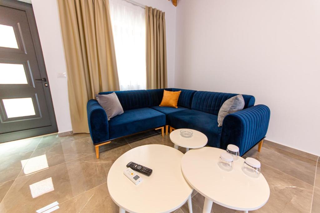 a living room with a blue couch and two tables at Santa Oliva Suites in Ksamil