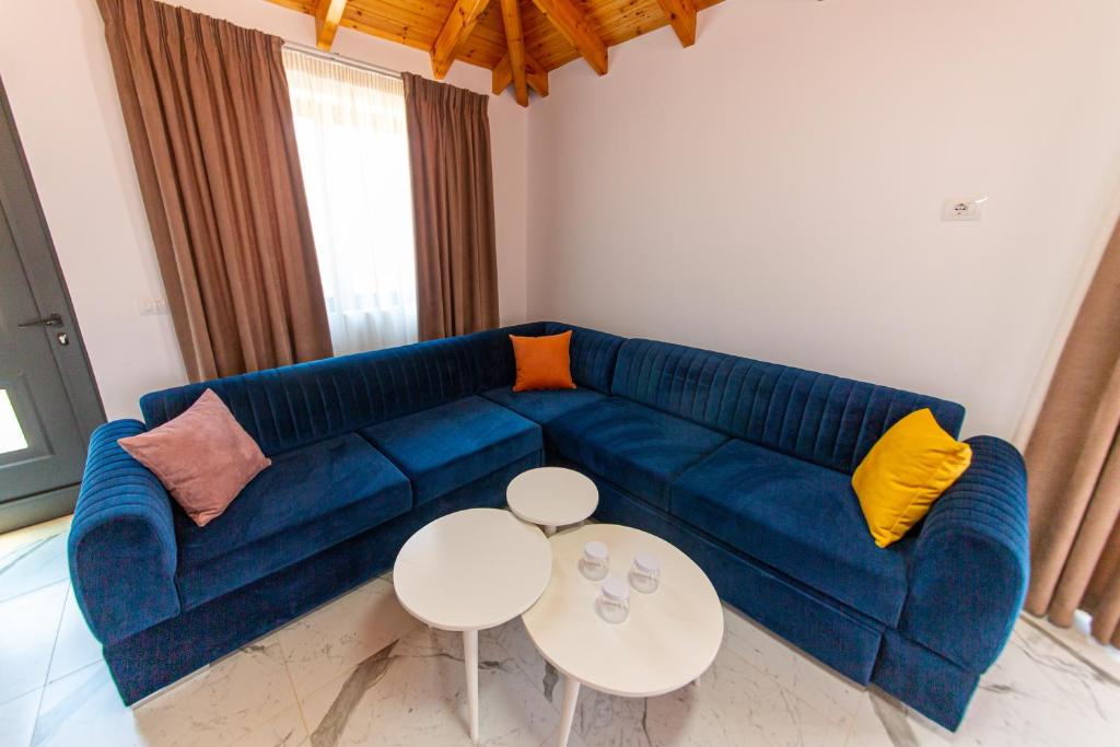 a living room with a blue couch and two tables at Santa Oliva Suites in Ksamil
