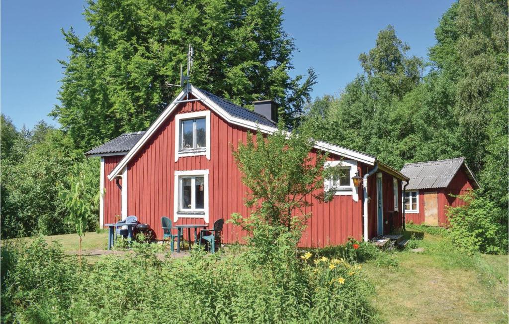 een rood huis met een tafel en stoelen ervoor bij Awesome Home In Ljungby With Kitchen in Bolmen