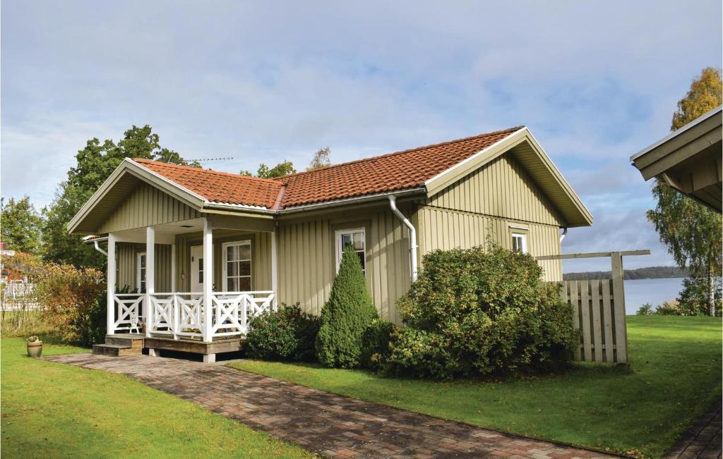 een klein geel huis met een witte veranda bij 4 Bedroom Stunning Home In Ljungby in Bolmstad