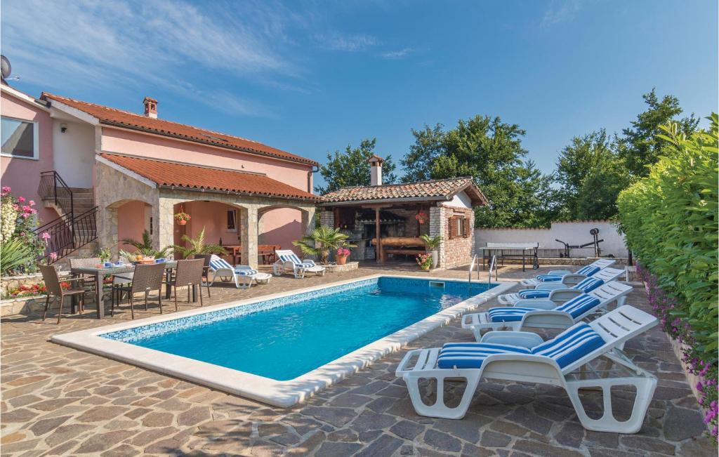 a swimming pool with lounge chairs next to a house at Stunning Home In Labin With Outdoor Swimming Pool in Labin
