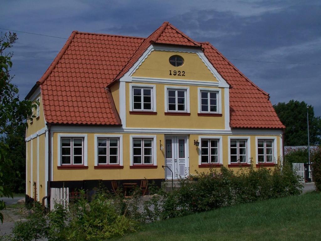 een geel huis met een rood dak bij Møllehusets Bed & Breakfast in Nordborg