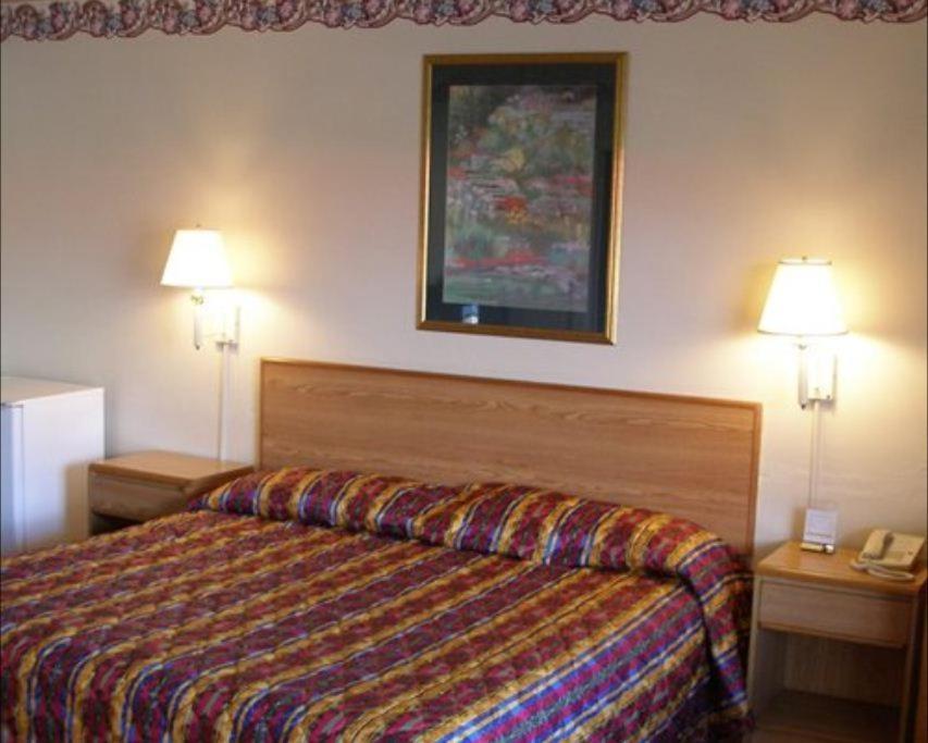 a hotel room with a bed and two lamps at Red Carpet Inn Starke in Starke