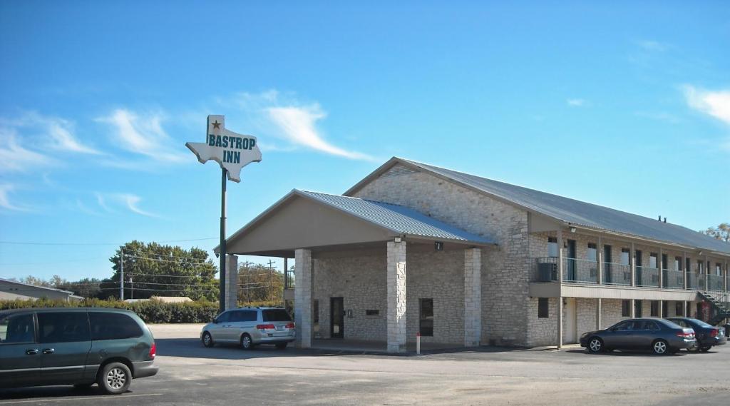 a building with cars parked in a parking lot at Bastrop Inn in Bastrop
