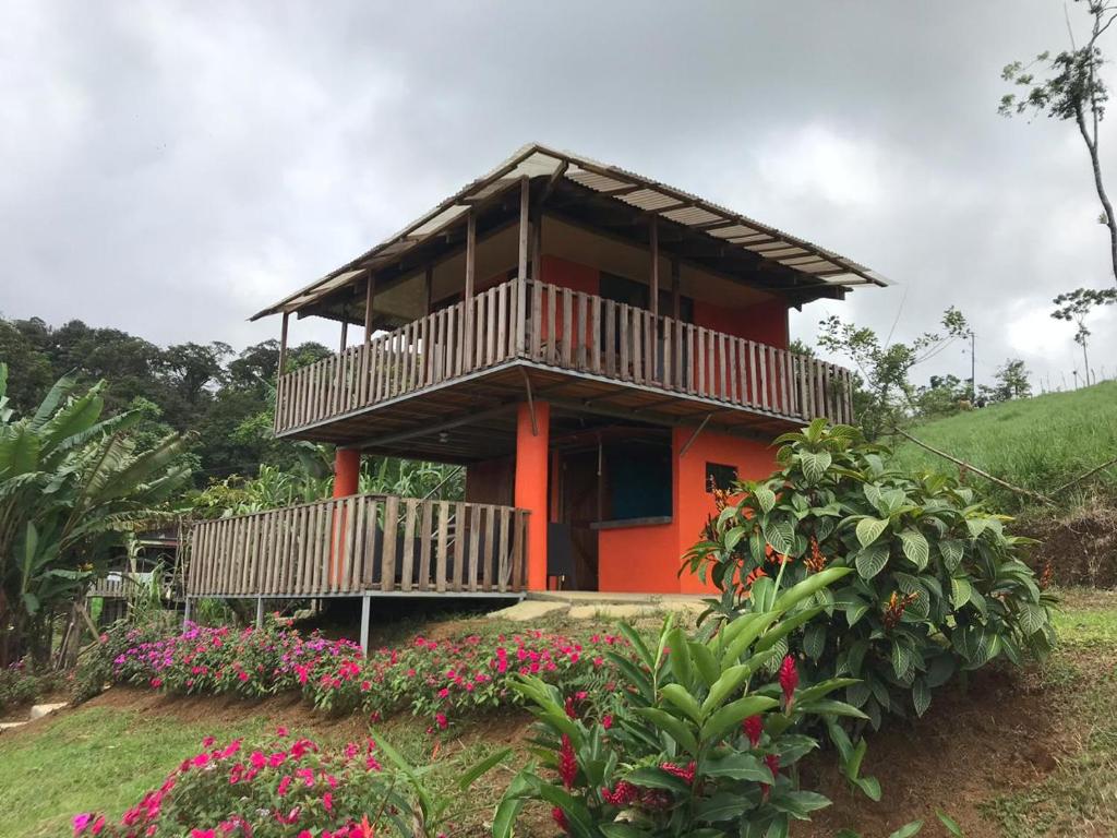 a red house with a balcony and some flowers at Cabaña La Piña in San Rafael