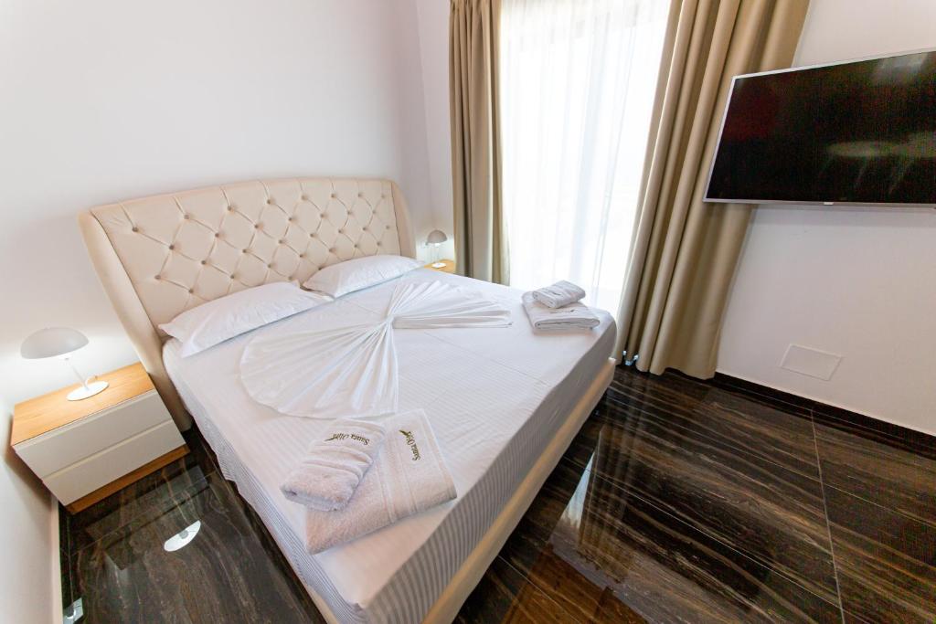 a bed with towels and a television in a room at Santa Oliva Suites in Ksamil