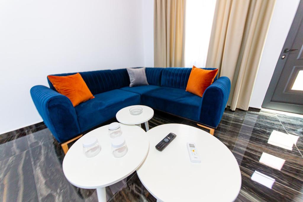 a living room with a blue couch and two tables at Santa Oliva Suites in Ksamil