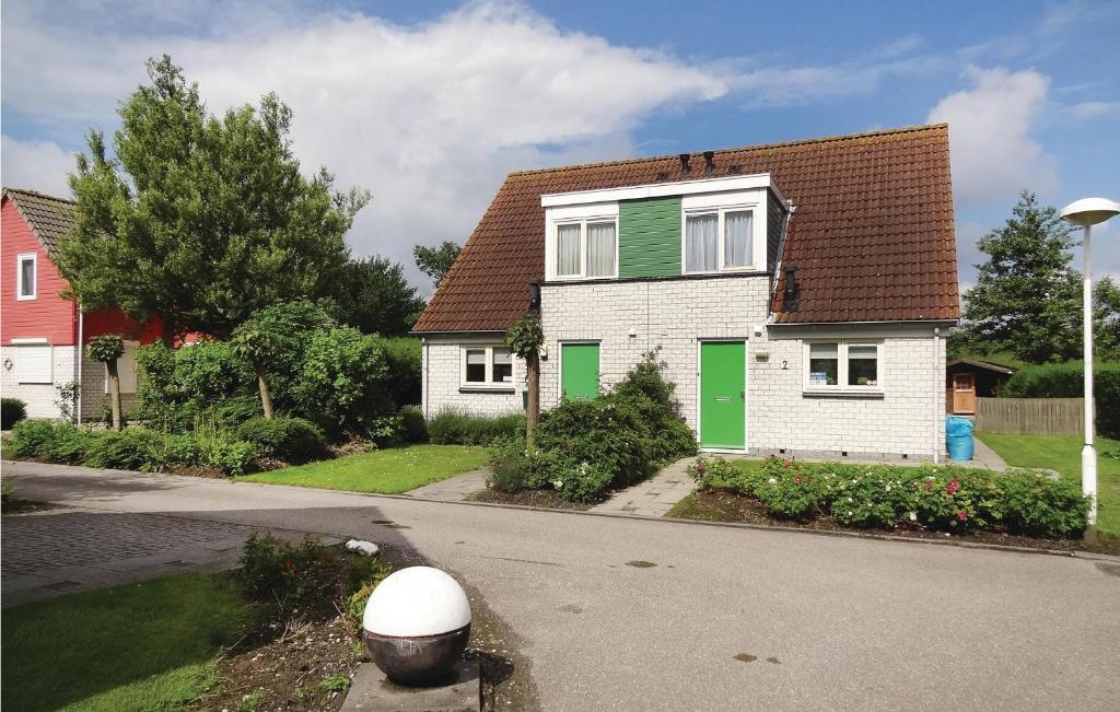 a white house with green shutters on a street at Oesterbaai -5c1 in Wemeldinge