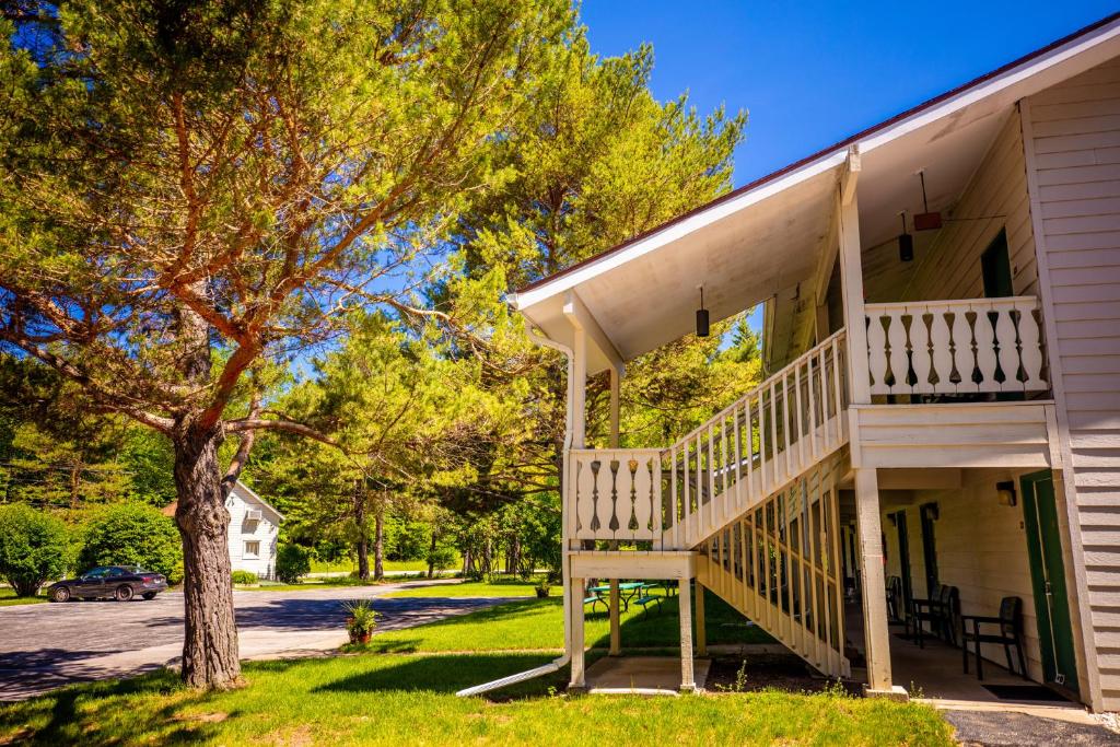 ein weißes Haus mit einer Veranda und einem Baum in der Unterkunft Parkwood Lodge in Fish Creek