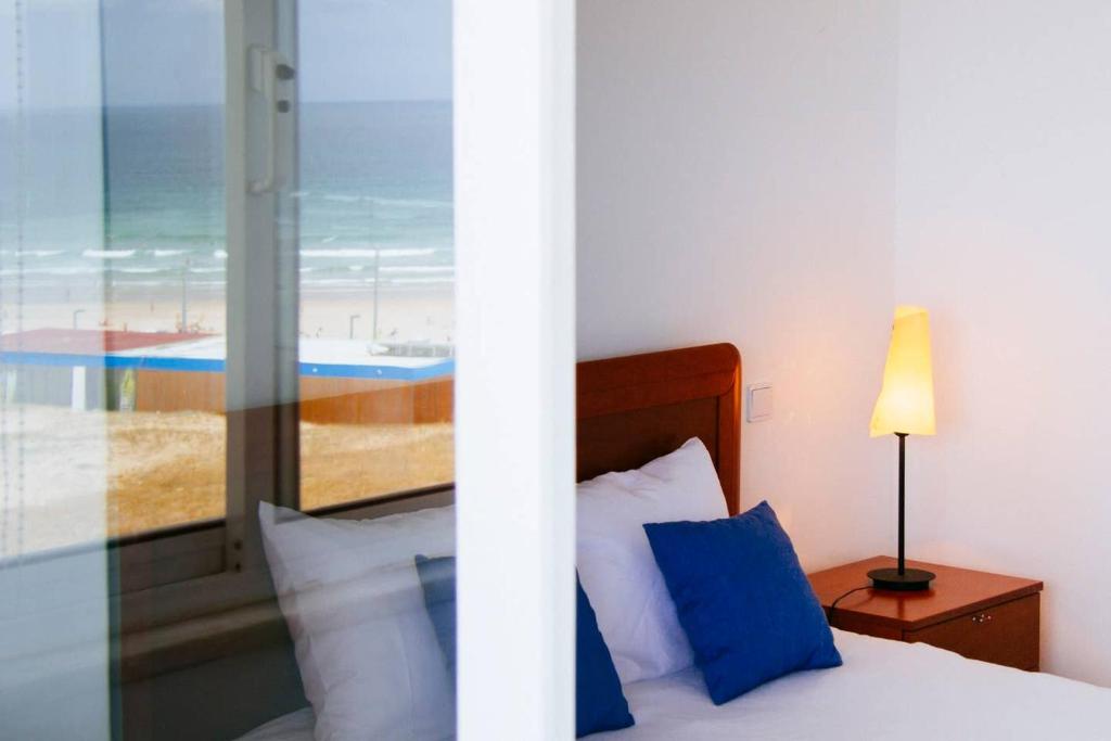 Panoramic Beach View Apartment (T2) in Caparica في كوستا دا كاباريكا: غرفة نوم بسرير مع اطلالة على الشاطئ