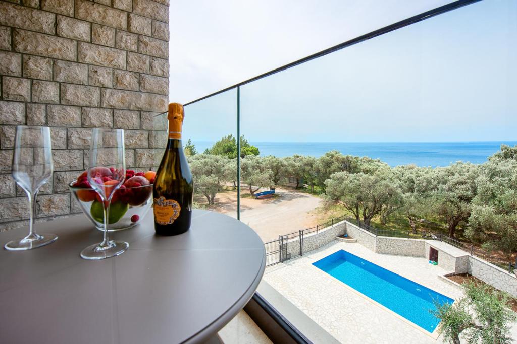 a bottle of wine on a table on a balcony with a view at Adria lux apartmens 2 in Sveti Stefan