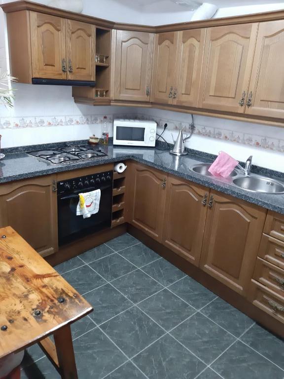 cocina con armarios de madera, fregadero y fogones en Casa Rocio, en Capileira