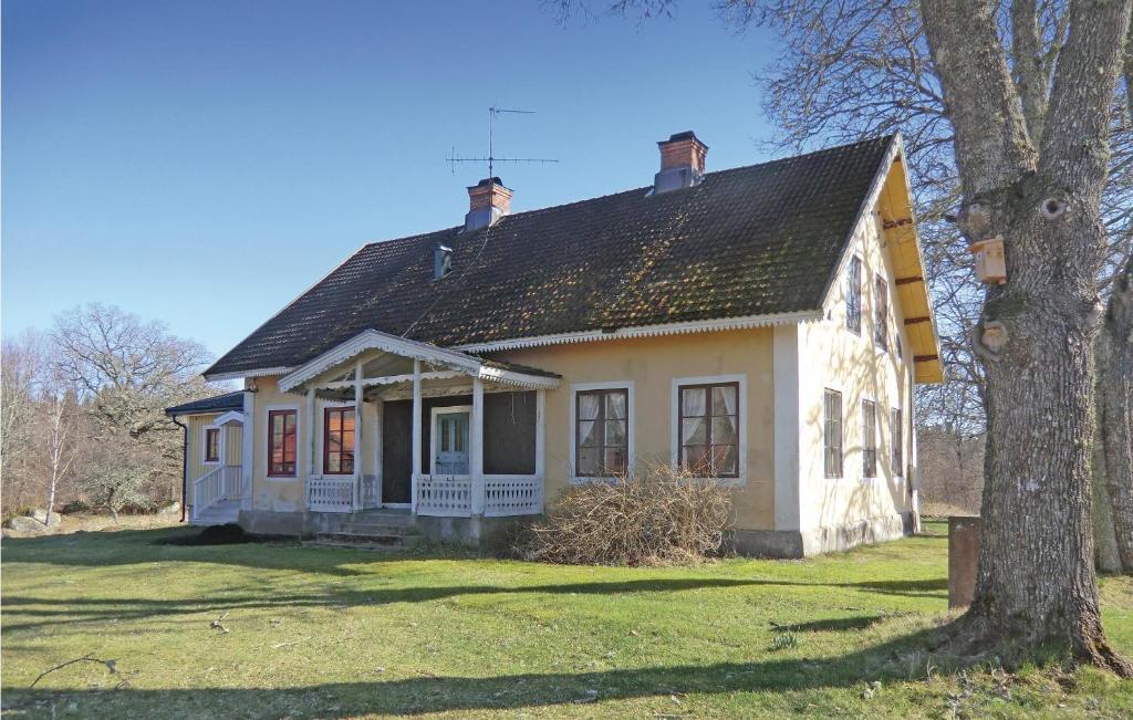 una pequeña casa blanca con un árbol delante en Beautiful Home In Hgsby With Kitchen en Fågelfors