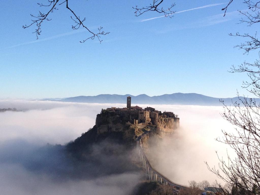 a castle on top of a mountain above the clouds at Civita B&B in Bagnoregio