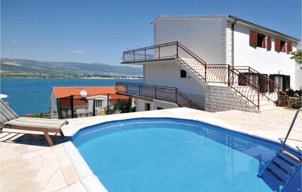 a swimming pool with a chair and a house at Cozy Home In Mastrinka With Sauna in Trogir