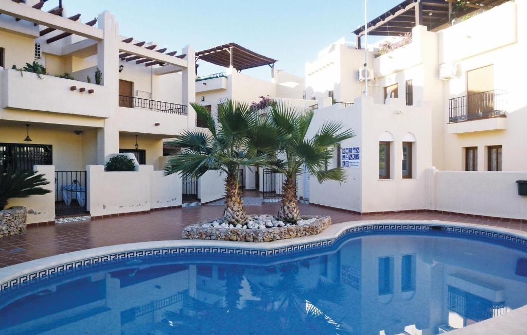 a swimming pool in front of a building with palm trees at Beautiful Home In Nerja With 3 Bedrooms, Wifi And Outdoor Swimming Pool in Nerja