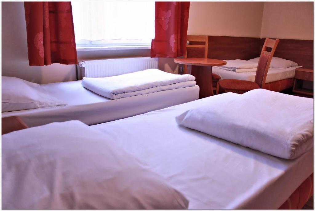 a room with three beds and a table and a window at City Hostel in Szczecin