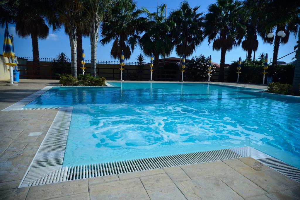 a large swimming pool with palm trees in it at Case Vacanze Ancora in Porto Empedocle