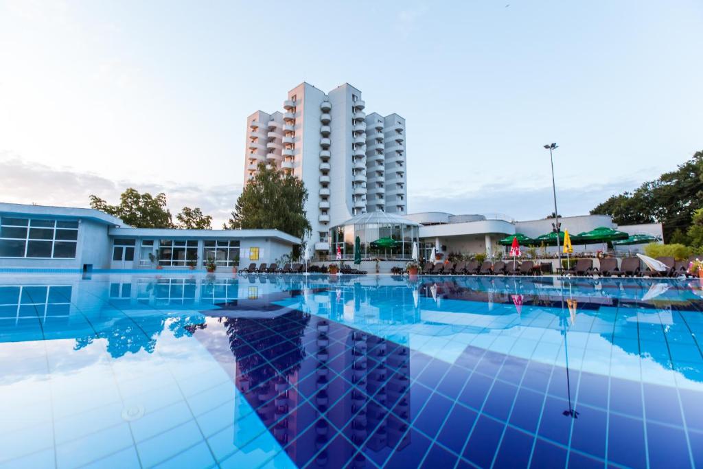 a large swimming pool with a building in the background at Hotel International in Baile Felix