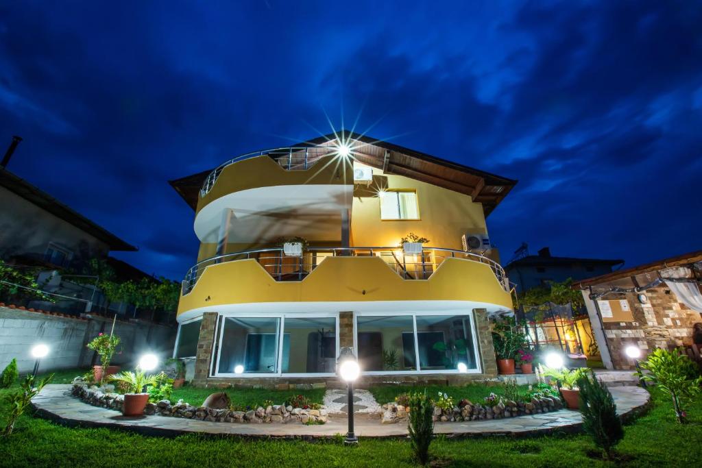 a large yellow house with lights on it at night at Guest House Holiday in Ognyanovo