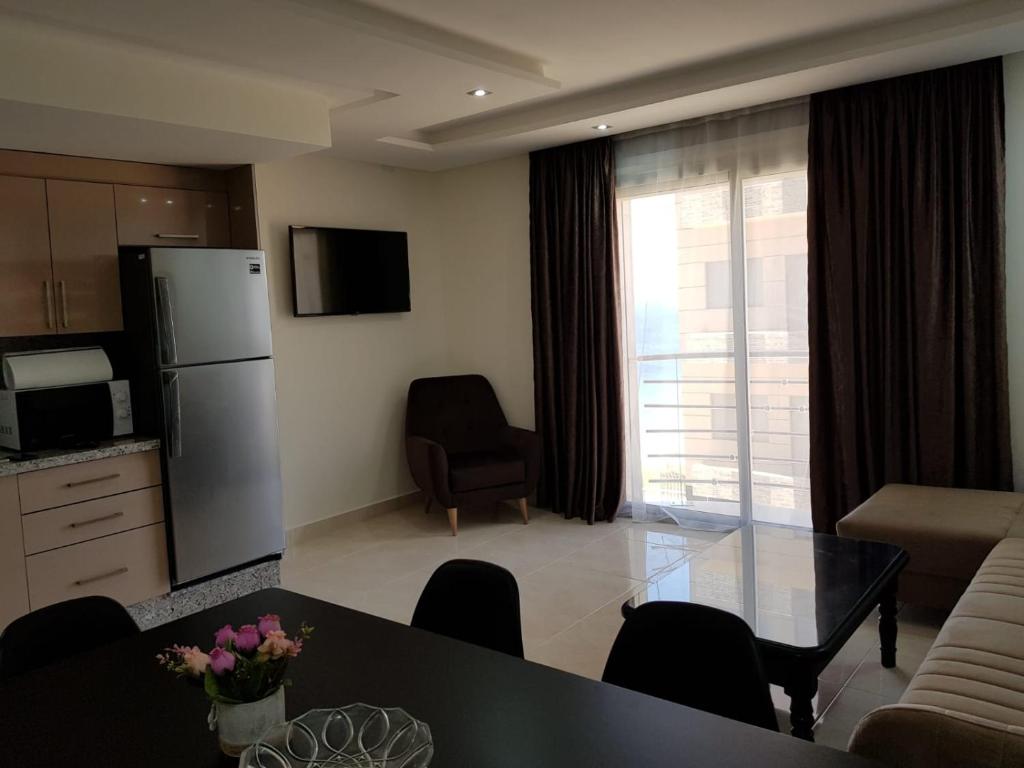 kuchnia i salon ze stołem i lodówką w obiekcie Saramica Seaside apartment w mieście Al-Funajdik