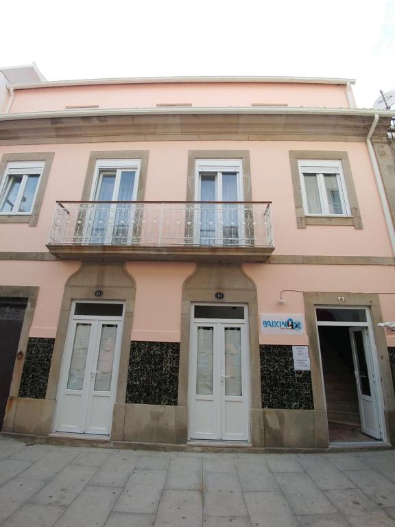 un bâtiment rose avec un balcon en haut. dans l'établissement Baixinho Guest House, à Vila Praia de Âncora