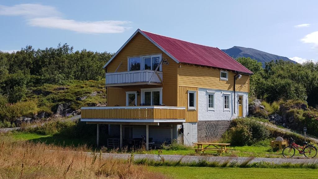 una casa con techo rojo en una colina en Farmer Apartment, en Laukvik