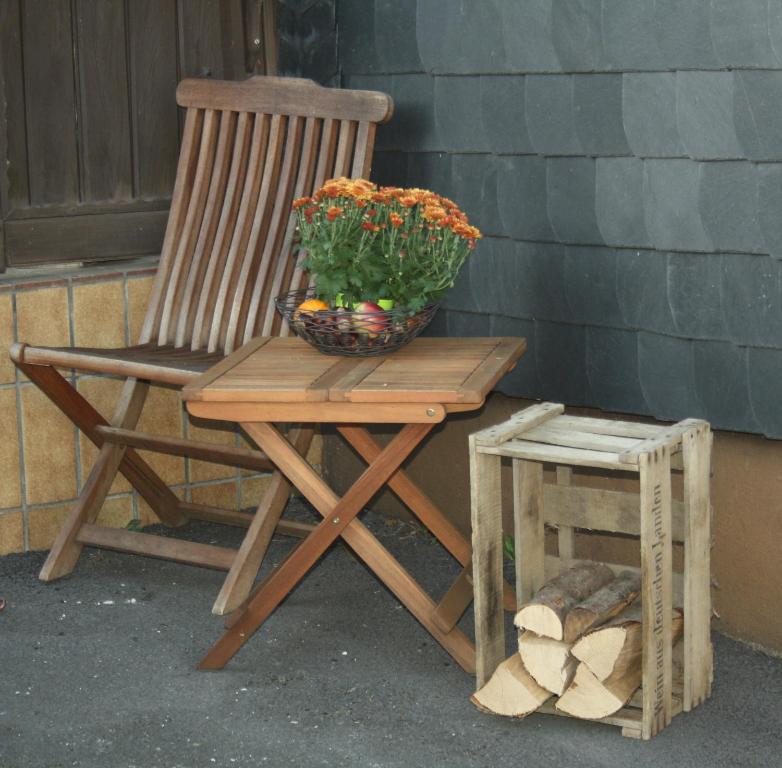 a wooden chair with a vase of flowers next to a stool at Ferienhaus Cilla in Beltheim