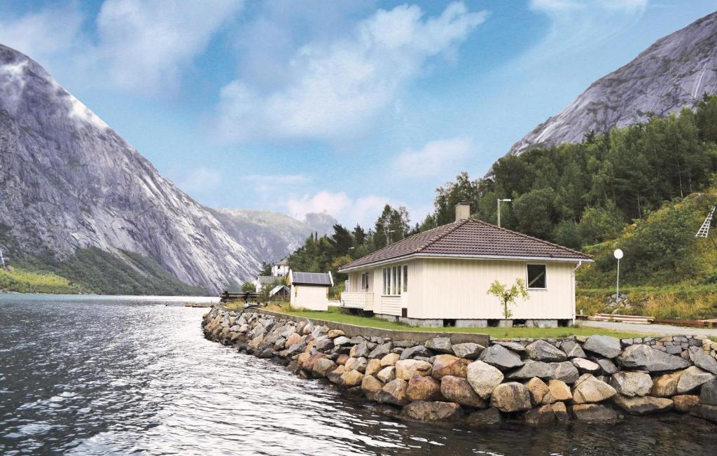 een huis aan het water met bergen op de achtergrond bij 3 Bedroom Cozy Home In Eidfjord in Eidfjord
