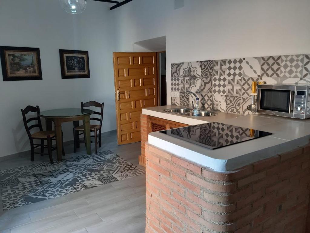 y cocina con encimera, microondas y mesa. en Casa Rural San blas, en Almagro