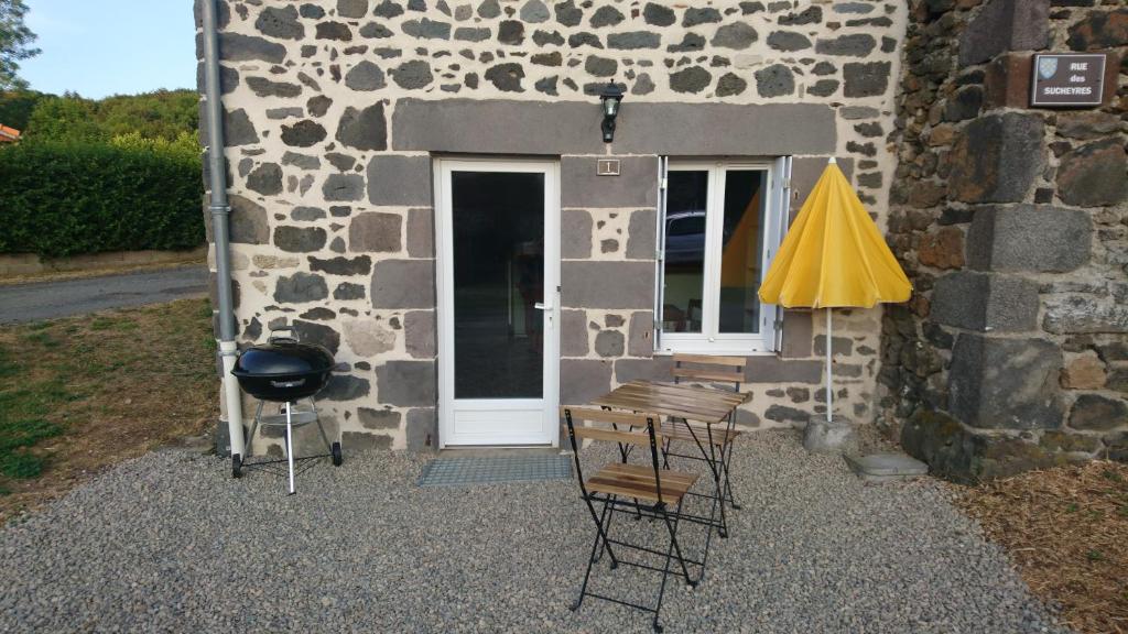 a patio with chairs and an umbrella next to a building at SEJOUR AU COEUR DES VOLCANS in Saint-Ours