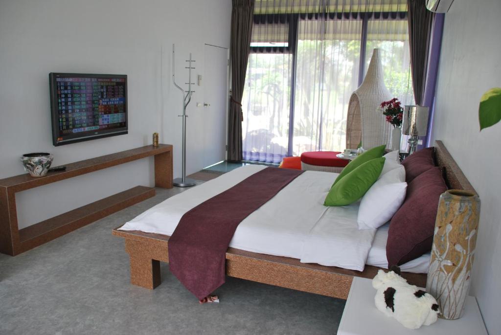 a bedroom with a large bed and a television at Lotus Hostel Beicheng Zhuang in Luodong