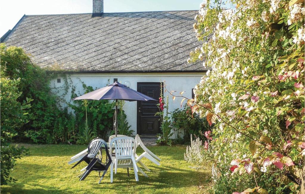 a couple of chairs and an umbrella in front of a house at Stunning Home In Ystad With Kitchen in Ystad