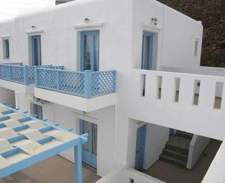 a white building with blue balconies and a staircase at Votsalo in Astypalaia