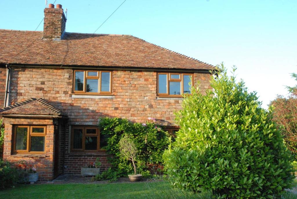 una casa in mattoni con un albero nel cortile di Hollyhock Cottage ad Ashford