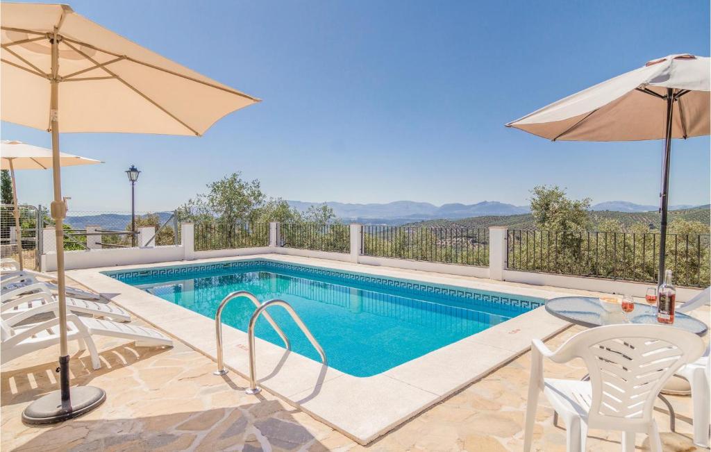 a swimming pool with a table and chairs and an umbrella at Awesome Home In Iznjar With House A Mountain View in Villanueva de Tapia