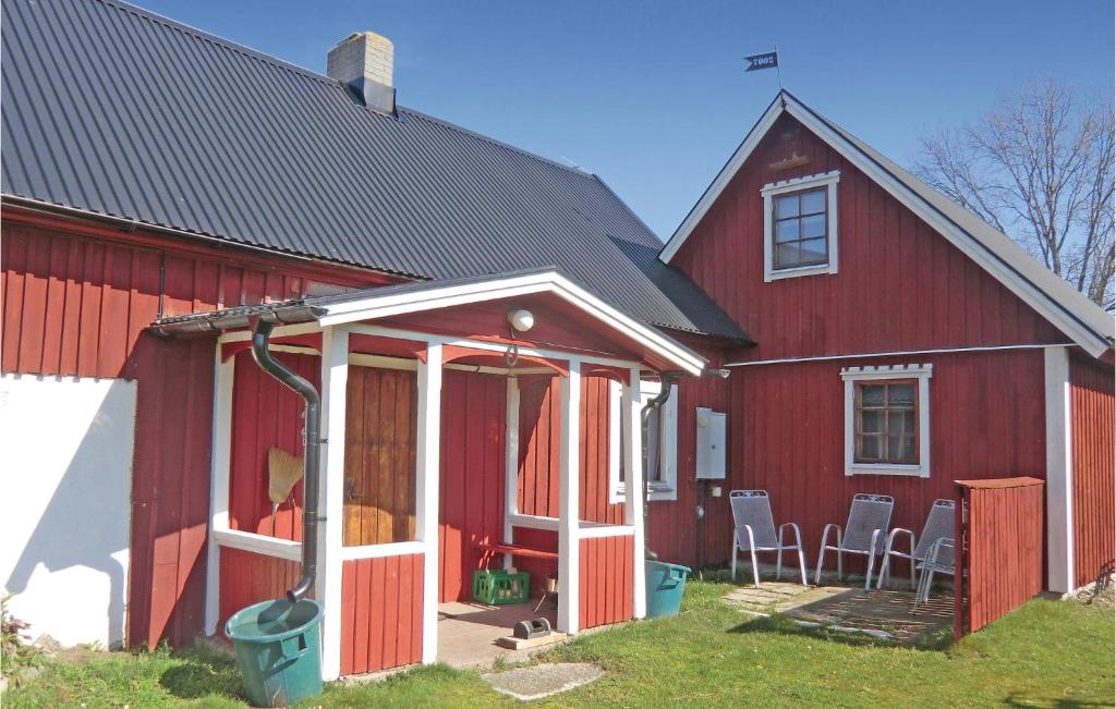 a red barn with a porch and chairs in front of it at Awesome Home In Lttorp With Kitchen in Löttorp