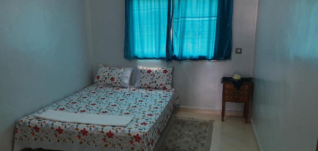 een kleine slaapkamer met een bed en blauwe ramen bij App Khouribga in Khouribga