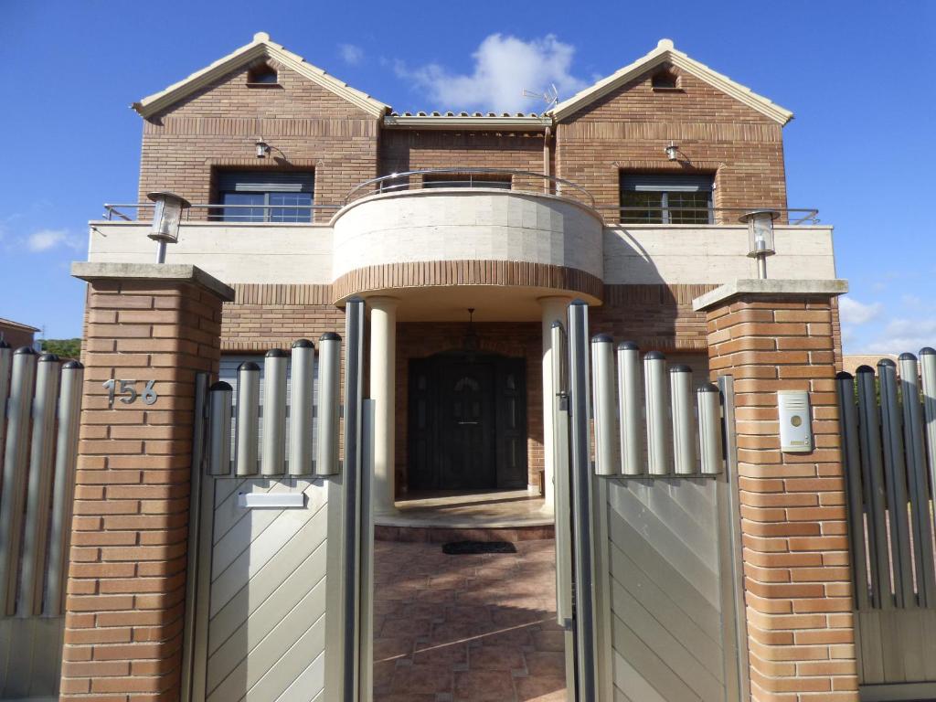 a brick house with a gate and a fence at Chalet moderno con PISCINA en Calafell in Calafell