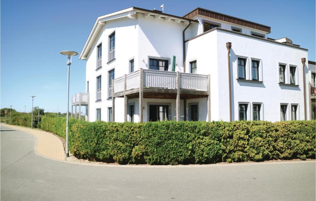 a white house with a balcony on a street at Amazing Apartment In Börgerende in Börgerende-Rethwisch