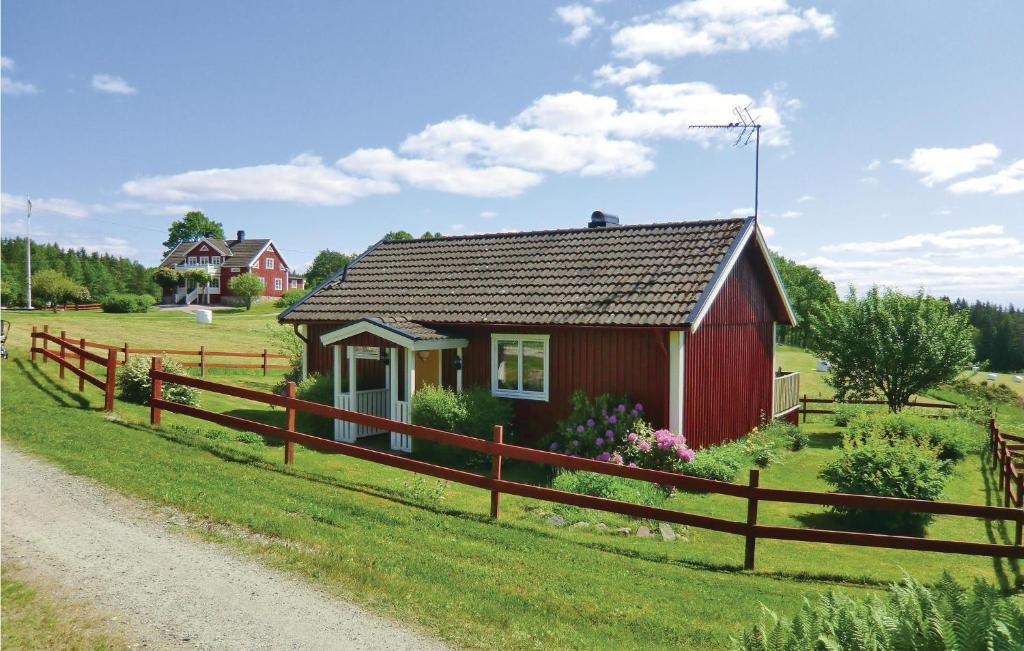a red house in a field with a fence at Stunning Home In Landsbro With Kitchen in Landsbro