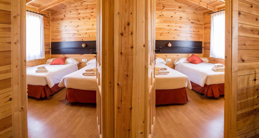 a room with two beds in a log cabin at Cabañas de Javalambre in Camarena de la Sierra