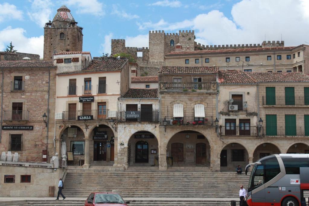 Alojamientos Plaza Mayor في تروخيلو: مجموعة مباني بها درج وقلعة