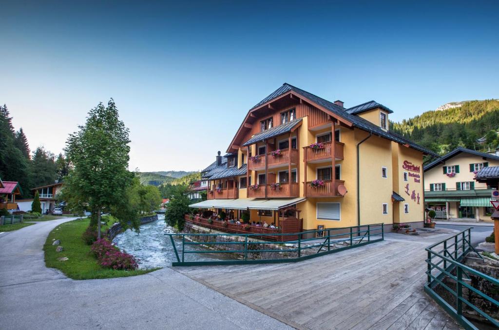 un grand bâtiment avec une rivière en face dans l'établissement Sporthotel Dachstein West, à Annaberg-Lungötz