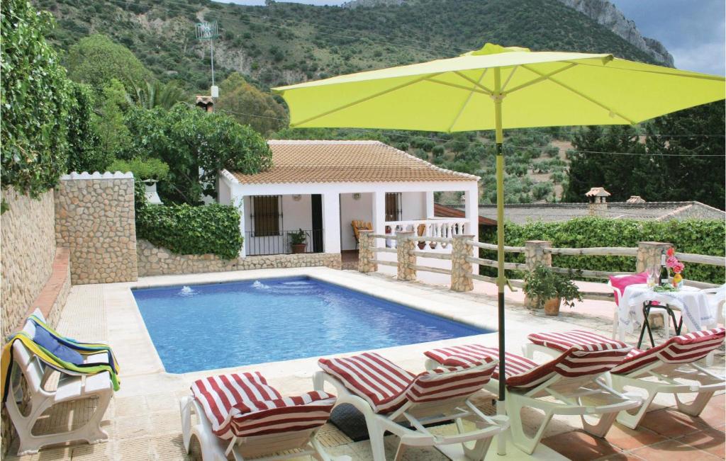 a pool with chairs and a yellow umbrella at Awesome Home In El Gastor With 2 Bedrooms, Wifi And Outdoor Swimming Pool in El Gastor